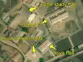 2/7 Another city centre regrouping a school (amenity=school), characterized by two long buildings (building=school) with a large courtyard in front (cf. Schools, a juche study hall (amenity=community_centre), with its specific shape, the immortality tower (historic=memorial and memorial=immortality_tower), with its shadow on the ground, and the city hall (amenity=townhall) (Maxar satellite imagery).