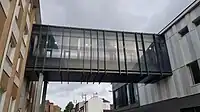 Стеклянный коридор, расположенный над землёй, соединяет два разных здания.