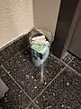 A cup full of tampons and pads in different sized on the floor