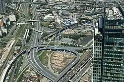 The construction site in July 2020. A distinctive feature of the skyscraper is that it will be built inside a turning overpass shown in the photo.