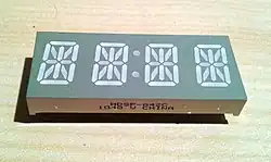 A four-character 14-segment clock display. Note unbroken top and bottom segments in comparison with a sixteen-segment display.