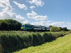 Shot of a field with a train running along a straight track in the distance
