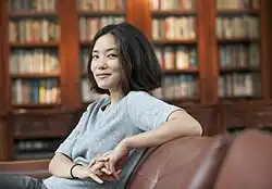 Ada Zhang sitting on a couch in front of bookshelves.