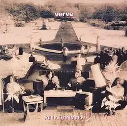 A sepia toned photograph of four men sat down with a fountain, path and trees behind them
