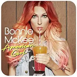 McKee wearing a denim tanktop sipping on an orange-red Slurpee drink.