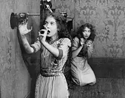 Black and white film still showing two young women in 1912 period dress