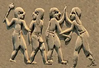 Shaven-headed attackers armed with maces and knives, against unarmed opponents with long hair, all wearing penile sheaths (Front, 1st register).[38][39]