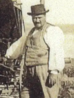Black and white photo of a black man wearing a white shirt, vest, and hat