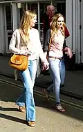 Two women wearing flared trousers, jeggings and oversized cardigans, 2011.
