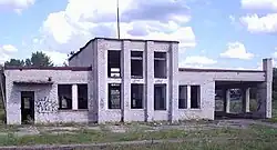 A derilict white onestory building.