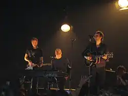 Three men on stage playing instruments