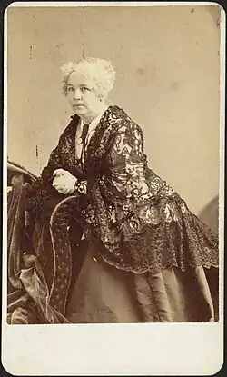 Photograph of Elizabeth Cady Stanton leaning on a piece of furniture and turning toward the camera