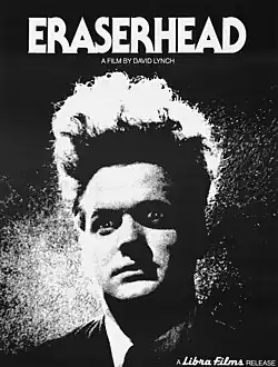 Black and white image of a man with long wild hair standing straight up, as if electrocuted like a cartoon