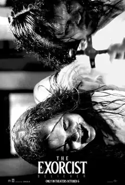 A black-and-white photo of a hand holding out a cross in front of two possessed girls.