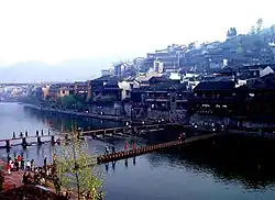 Traditional houses at a river and people crossing on two bridges made of stones