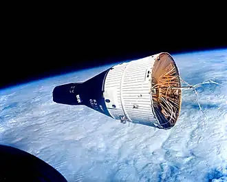 A black and white spacecraft, with the Earth below it.