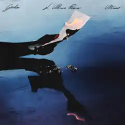 A man's hand holding a burning piece of paper over a reflective blue surface.