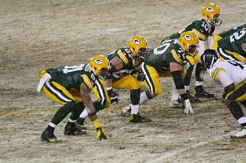 American Football players line up against each other and crouch down into an isometric press position. This allows them to rush forward more powerfully when the play begins; this is particularly useful in regard to tackling or blocking an opponent.
