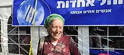 Photograph of Froman. She is smiling, wearing a green head covering and a red floral top.