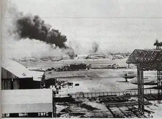 Photograph of the city and trees with an explosion on the horizon
