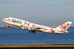 An aircraft taking off from the runway, with a city skyline on the background