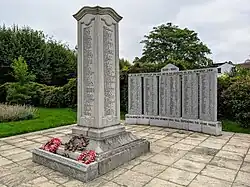Two memorials, one a four-sided stone pillar, the other a stone arc. Both are inscribed with names
