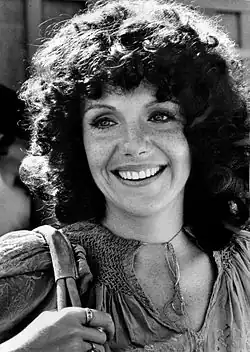 Black and white headshot photograph of a woman with shoulder-length curly hair