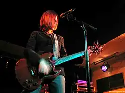 A worm's eye-view of a Caucasian woman with medium-length brunette hair playing guitar