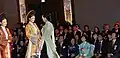 The two women that are wearing the áo dài are both wearing a kiềng.