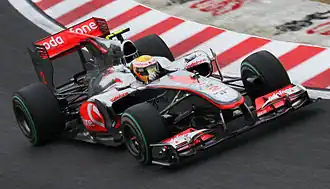 A silver-and-red single-seater racing car is driven around a tarmac course.