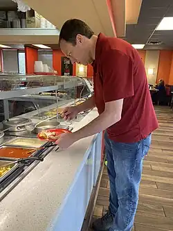 A customer gets food from a buffet in a restaurant.