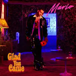 Mario leans against a mirrored wall in a 1970s-style room, giving a seductive look as he holds a red rotary telephone; its cord draped around his neck.