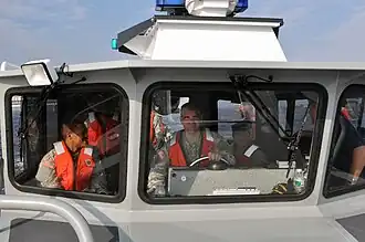 Members of the New York National Guard take the helm of a New York State Naval Militia patrol boat.