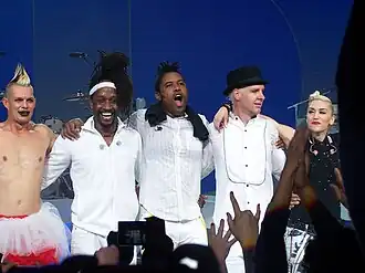 A color photograph of No Doubt posing together on stage after a performance.