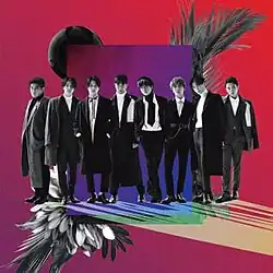 Eight Super Junior members standing in front of a purple screen and a red background behind it
