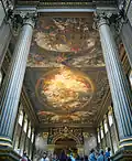 The Painted Hall at the Old Royal Naval College in Greenwich, London, England, designed by Sir Christopher Wren and Nicholas Hawksmoor. The paintings by Sir James Thornhill comprise architectural trompe-l'œil; for instance, the Corinthian columns look fluted whilst the far wall depicts pilasters and an entablature. In practice none of these elements exist in three dimensions