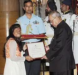 Woman on left receives award from man on right