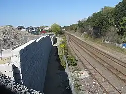 A below-grade railroad corridor, with a retaining wall and construction site at left