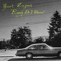 A grayscale photo of a car driving past trees