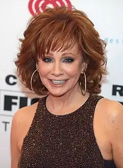 A woman with bright red hair smiles toward the camera.