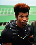 Richard Browne, wearing a black T-shirt with sponsors logos and a black backpack