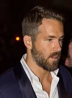 Reynolds with a blue suit talking to someone