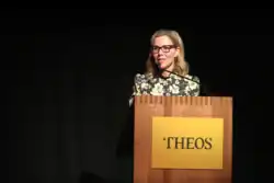 Sally Phillips standing at a pulpit with the Theos logo giving a lecture