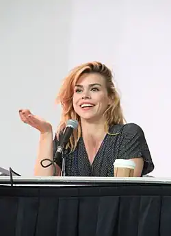 Billie Piper in a red shirt against a blue background