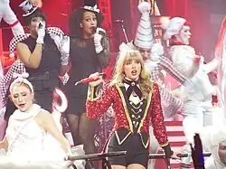 Swift (center) wearing a red sequined coat as her dancers dressed as circus characters