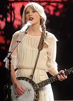 Swift in a white blouse playing a banjitar