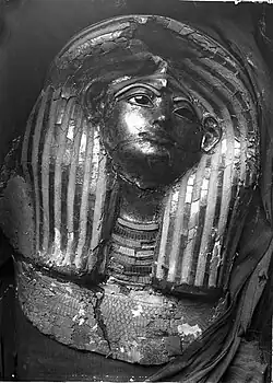 Damaged painted and gilded mask with a missing eye and large collapsed area on the front of the head