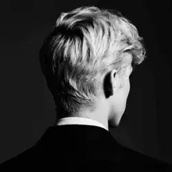 A black-and-white photo of Sivan from behind, who is facing slightly to the right and is wearing a suit and shirt.