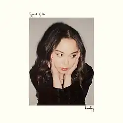 Laufey from the waist up on a gray background wearing a black long-sleeved shirt with her hands on the sides of her face and looking lost, the EP title and the artist's name are in the white border around the image