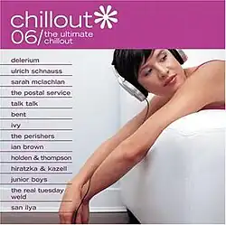 A woman wearing a pink tank top lounges on a white chair with headphones on; above her, the title of the album is visible on a pink background in a white font.